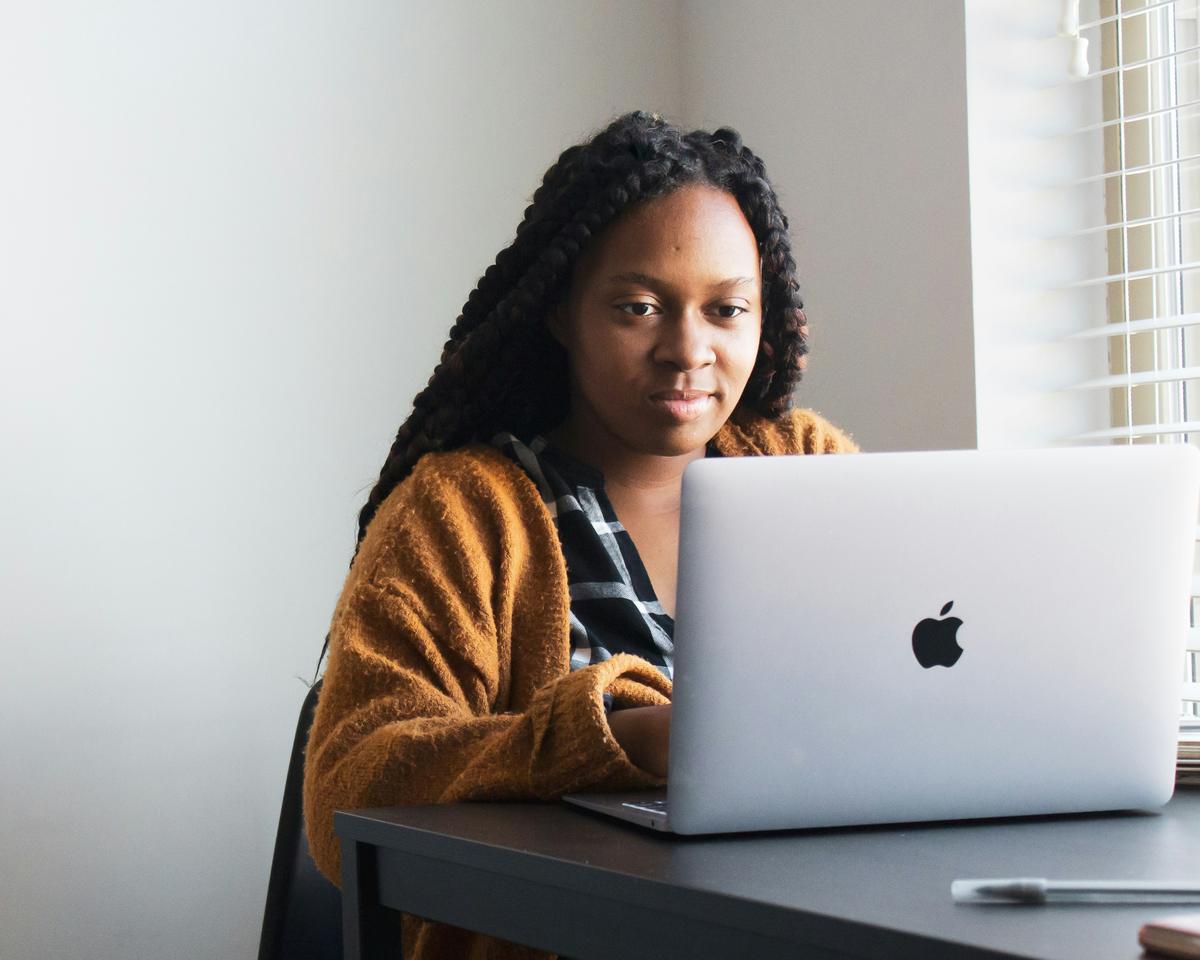 A student smiling at her laptop by a window
